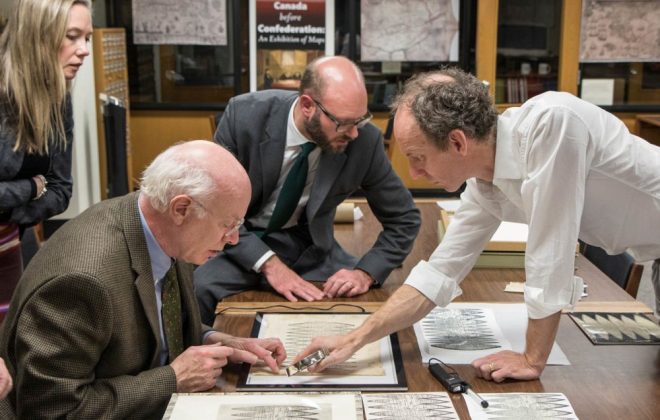 Representatives from Christie’s examine the Bell Library’s print of the Waldseemüller map