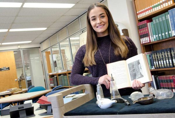 Bridget McKenna in the Wangensteen Library, holding a book on historic infant feeding.