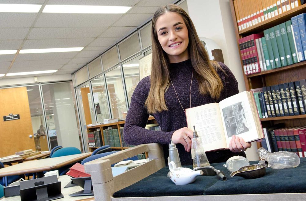Bridget McKenna in the Wangensteen Library, holding a book on historic infant feeding.
