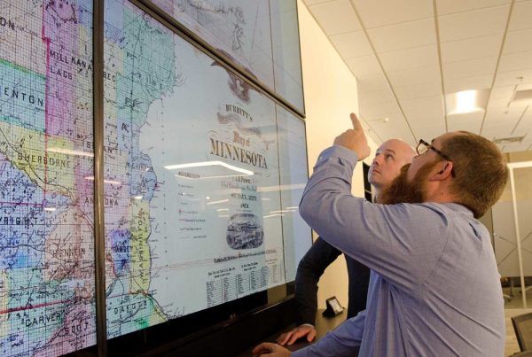 Ryan Mattke, Map & Geospatial Information Librarian, points out details on an 1871 map of Minnesota to Benjamin Wiggins, Program Director of the Digital Arts, Sciences, & Humanities (DASH) program.