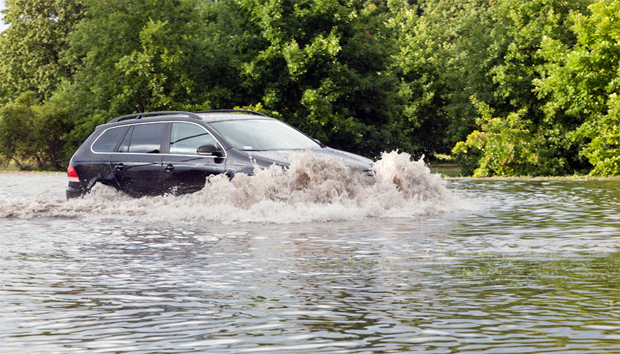 Photo of car driving through flood water.