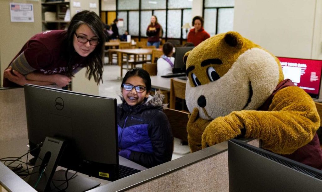 Alicia Kubas, left, and Goldy help out a student on History Day at Wilson Library.