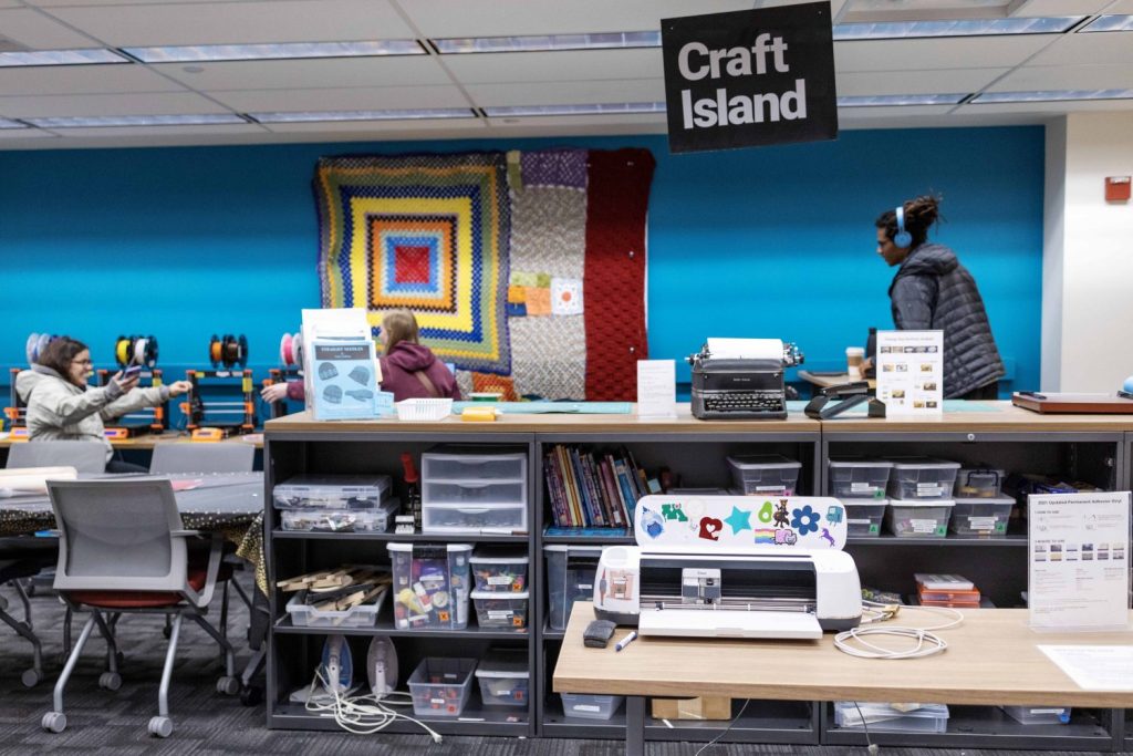 The Breakerspace at the Toaster, with a sign that says "Craft Island" hanging from ceiling. Counter with typewriter and craft supplies