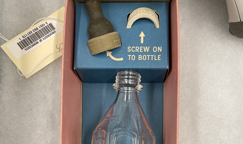 Glass infant feeding bottle with plastic screw top to affix a rubber nipple in original cardboard box.