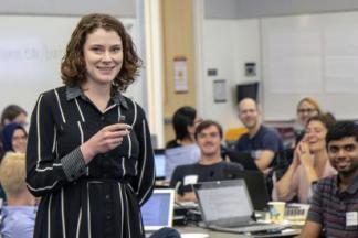 Photo of Caitlin Bakker teaching in front of a classroom