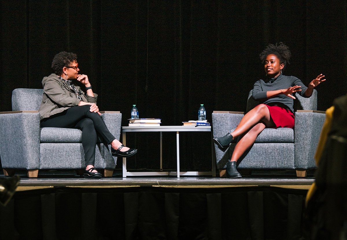 Two presenters on a stage sitting in armchairs