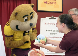 Goldy Gopher inspects a model human skull at the UMN Health Sciences Library's booth.