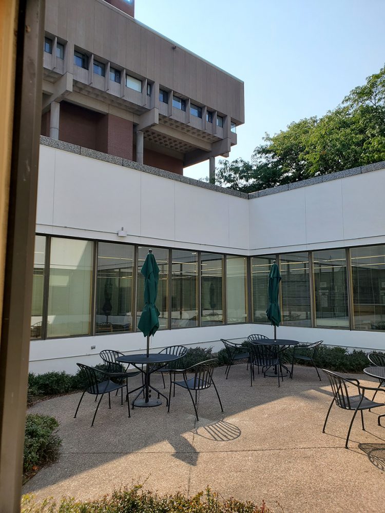Round tables and chairs arranged on the patio outside of the Music Library.