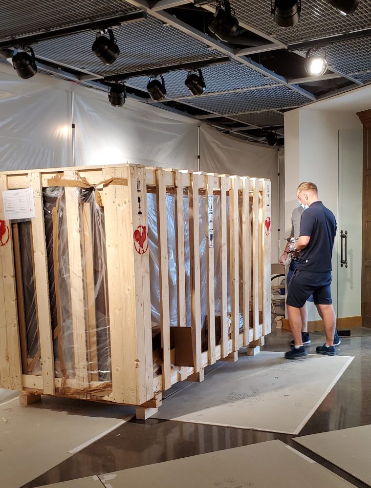 Large wooden crate with man preparing to unpack.