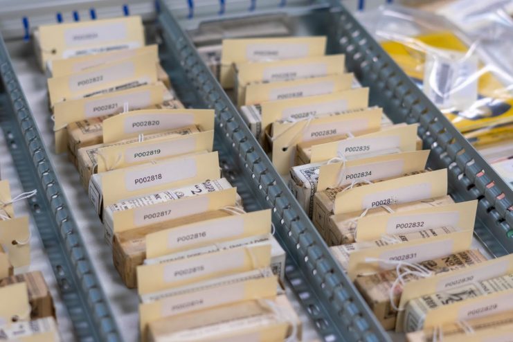 A collection of artifacts is seen in a metal tray, all with identification numbers tied to the packaging with string.