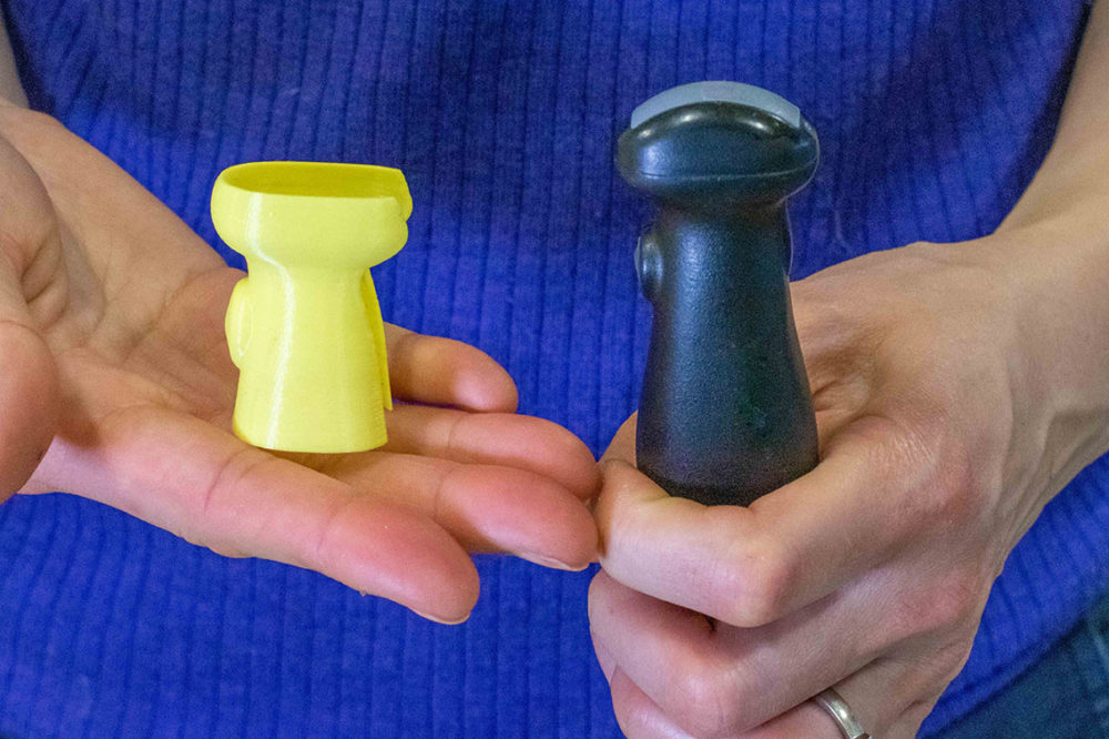 Rosalind Chow holds a probe cover in one hand and the ultrasound probe in the other to show how they fit