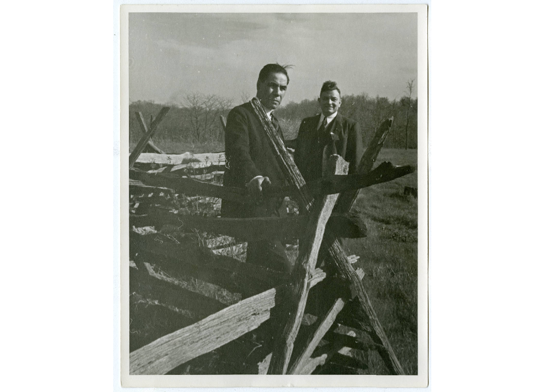 Joe Friday and Harold S. Keltner, YMCA Indian Guides founders, stand next to a split rail fence, between 1920 and 1949.