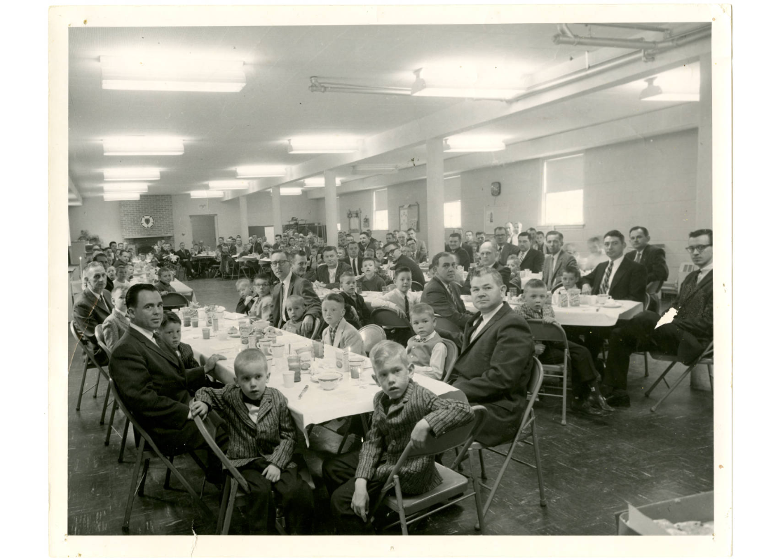 Minneapolis YMCA Minnetonka branch Indian Guides program father and son Good Friday breakfast at the Grace Lutheran Church in Deephaven, Minnesota, 1960. On the back of the photo there is a note, "150 in attendance. Weather good. Facilities crowded."