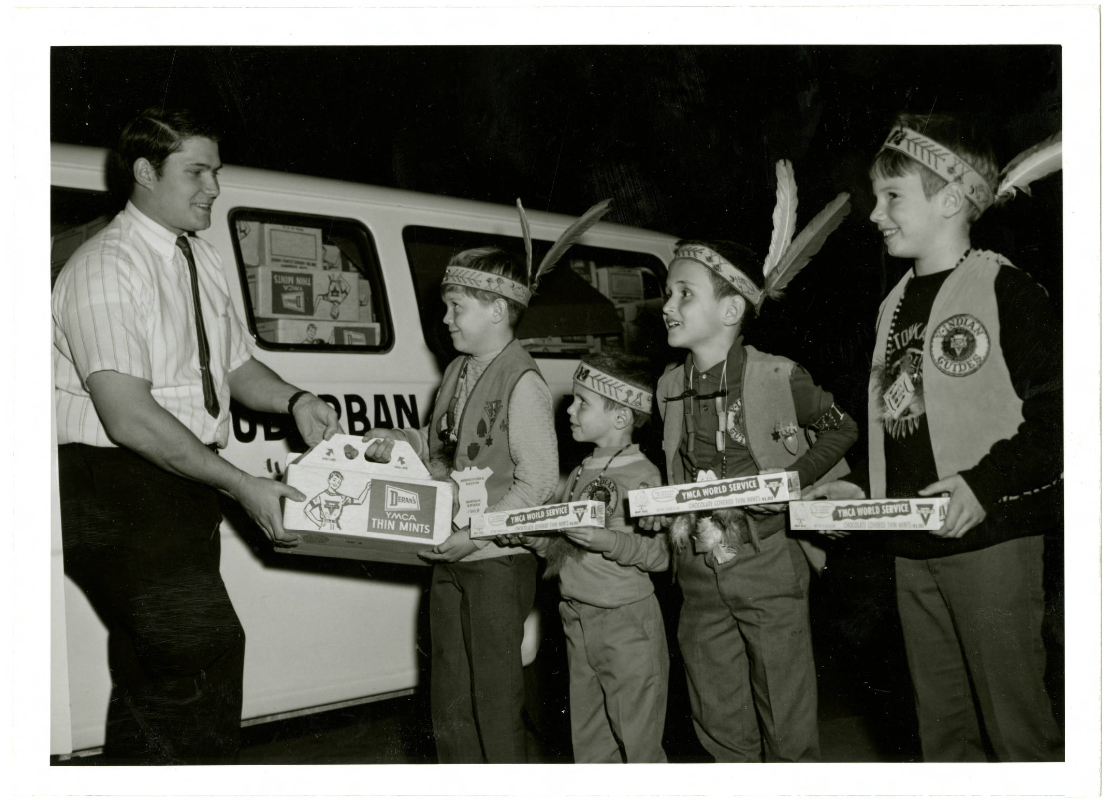 West Suburban Family Branch program director, Bill Strickland, passing out YMCA Thin Mints boxes to Indian Guide youth for their candy sale fundraiser, Minnetonka, Minnesota, 1969-1975.