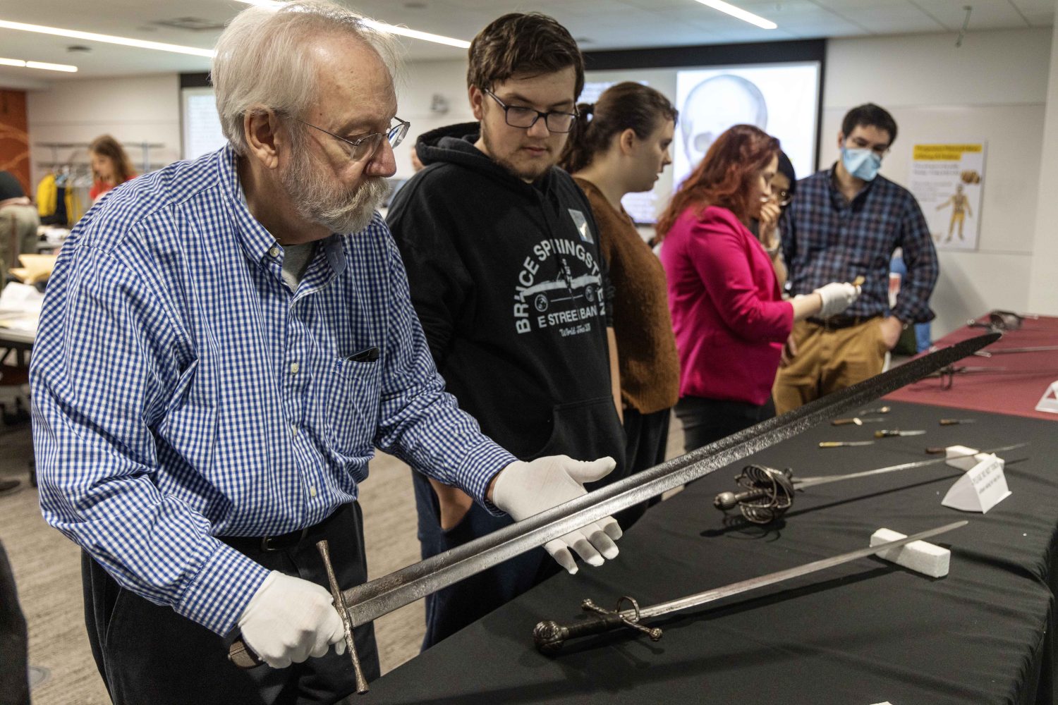 An attendee lifts an antique sword at the Wangensteen pop-up exhibit.