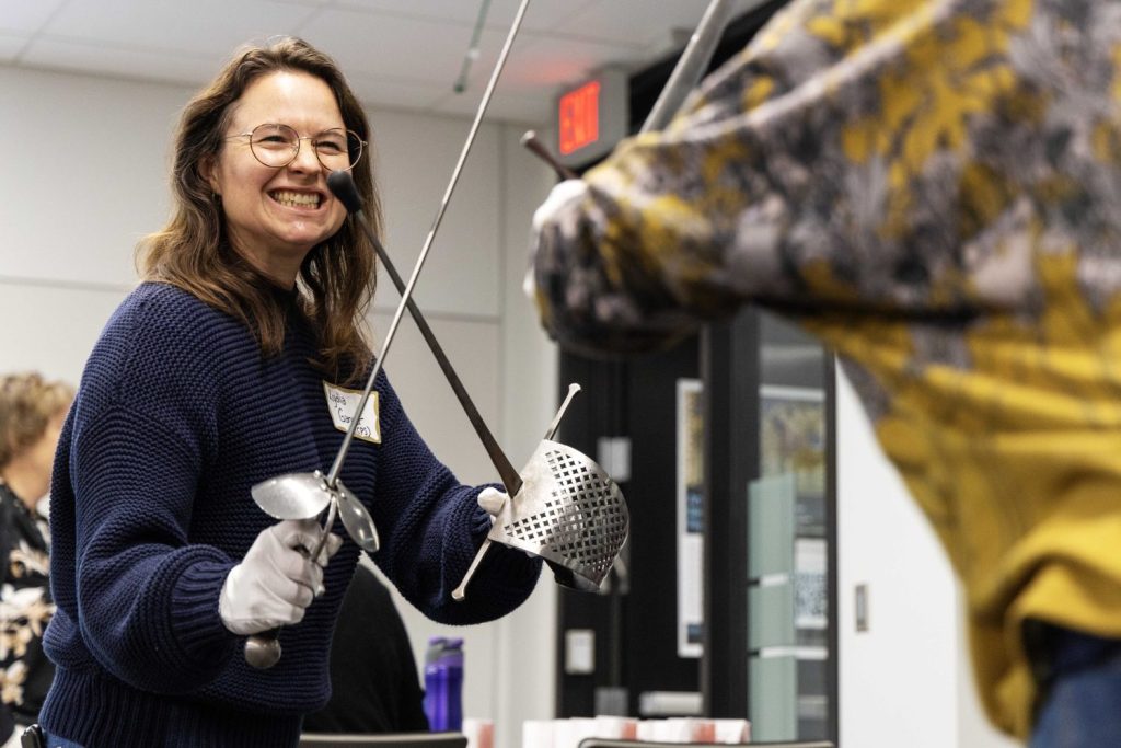 Associate Director of the Center for Premodern Studies Lydia Garver learns how to duel with swords at the Wangensteen pop-up exhibit.