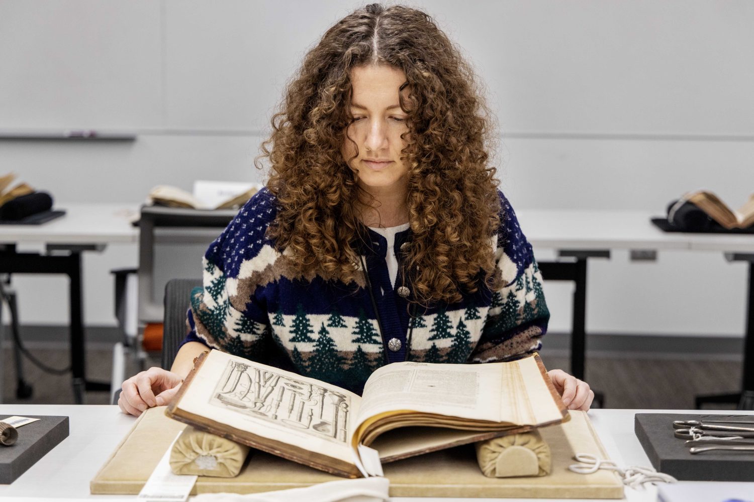 A student reads a rare book at the Wangensteen pop-up exhibit.