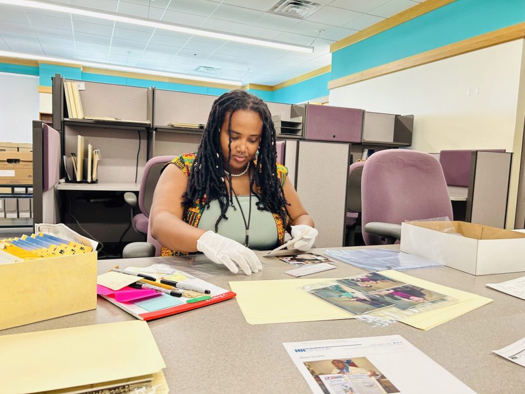 Ayantu Tibeso transferring photographs from original envelopes into archival sleeves for preservation.