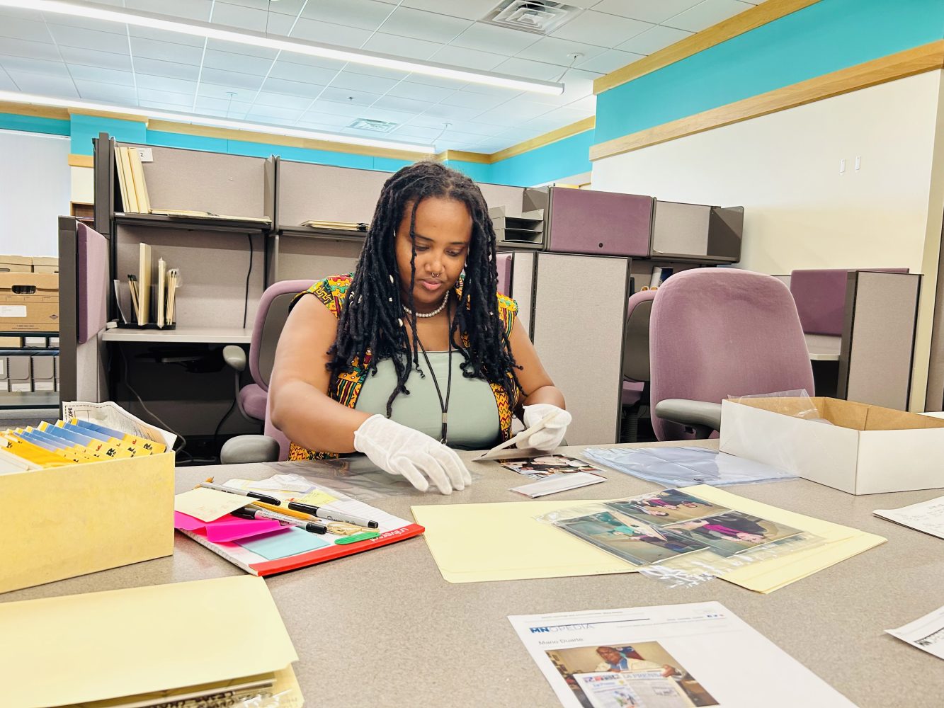 Ayantu Tibeso transferring photographs from original envelopes into archival sleeves for preservation.