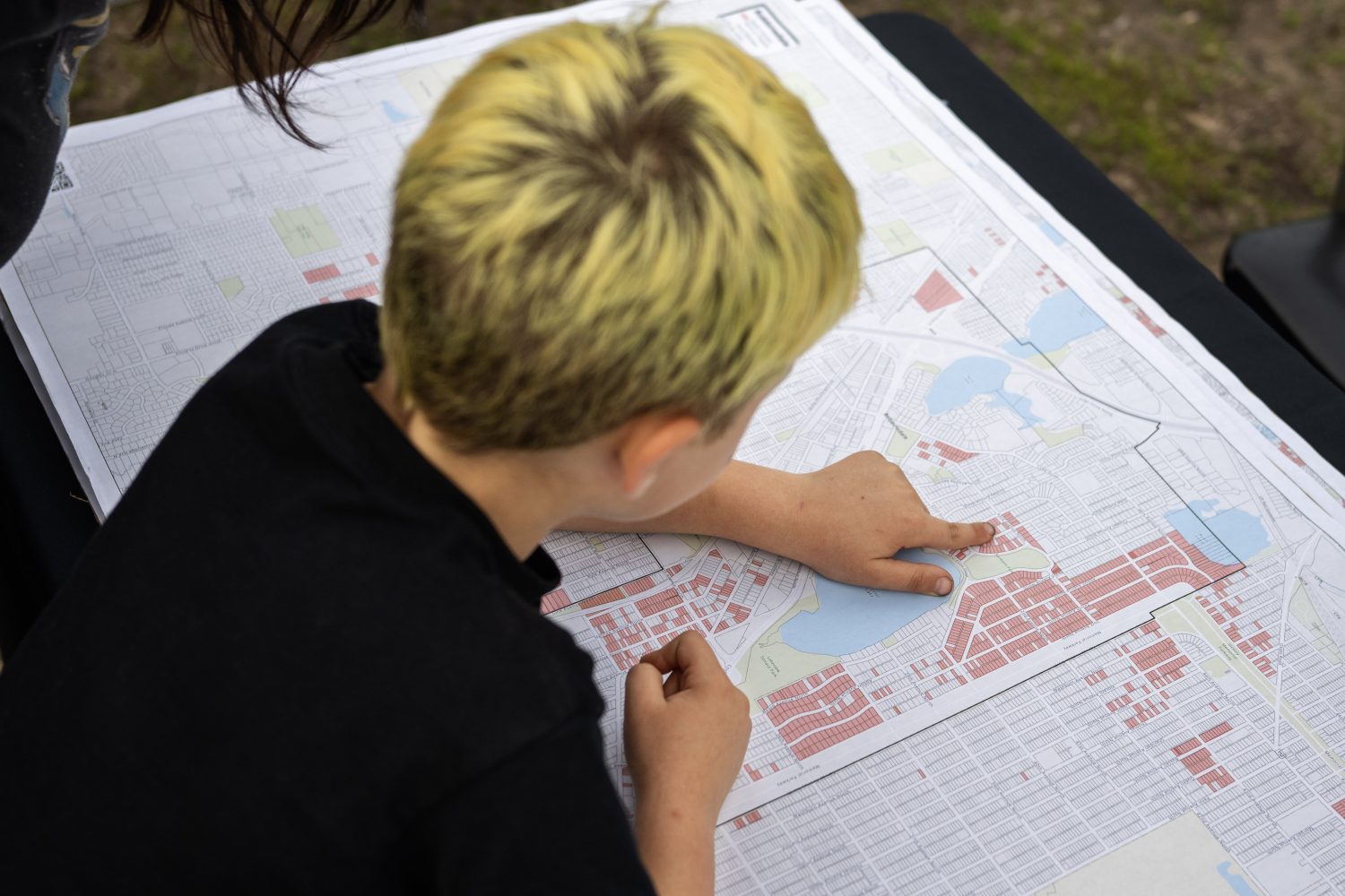 A young boy looks points to his street on a map of racial covenants in Robbinsdale, Minnesota, on Friday, May 3, 2024. (Photo/Adria Carpenter)