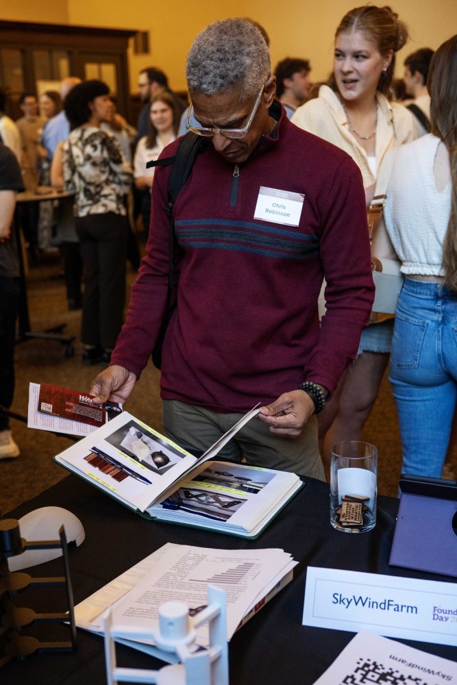 Chris Robinson looks through the brochure for SkyWindFarm, developed by Yash Dagade and Sayan Bishwa, during the Minimum Viable Product Challenge for Founder's Day at Walter Library on Wednesday, May 8, 2024. (Photo/Adria Carpenter)
