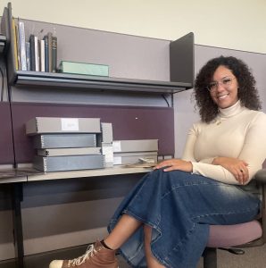 Addison Cox poses alongside the Givens Collection' catalog of sheet music that she helped curate, as well as the other materials from the archives.