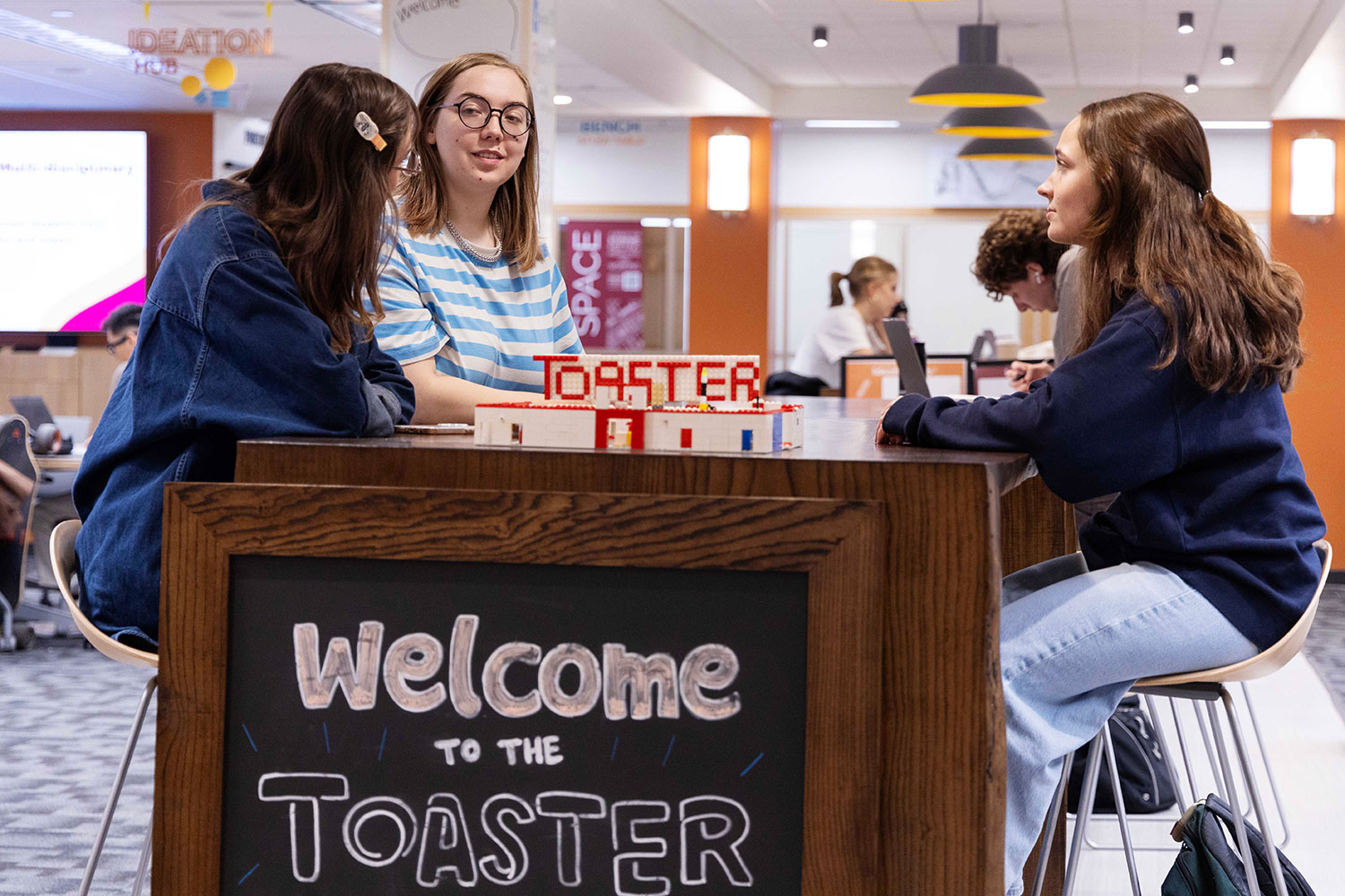 Three students gathered around a table in the Toaster Innovation Hub