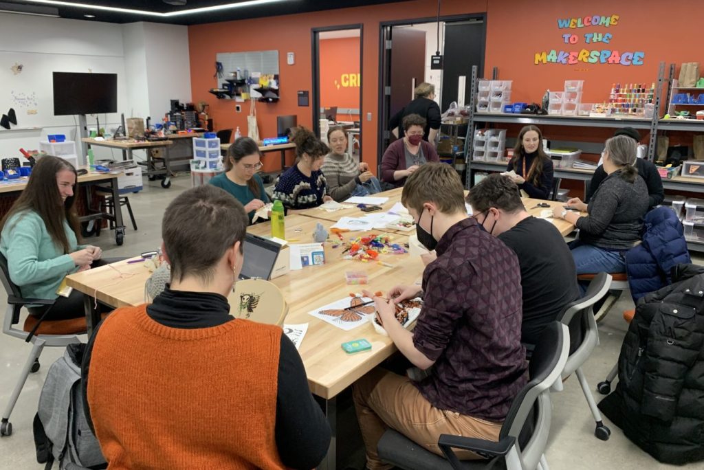 Group of UMN Libraries staff sit around a table and independently create art in the Health Science Library Makerspace